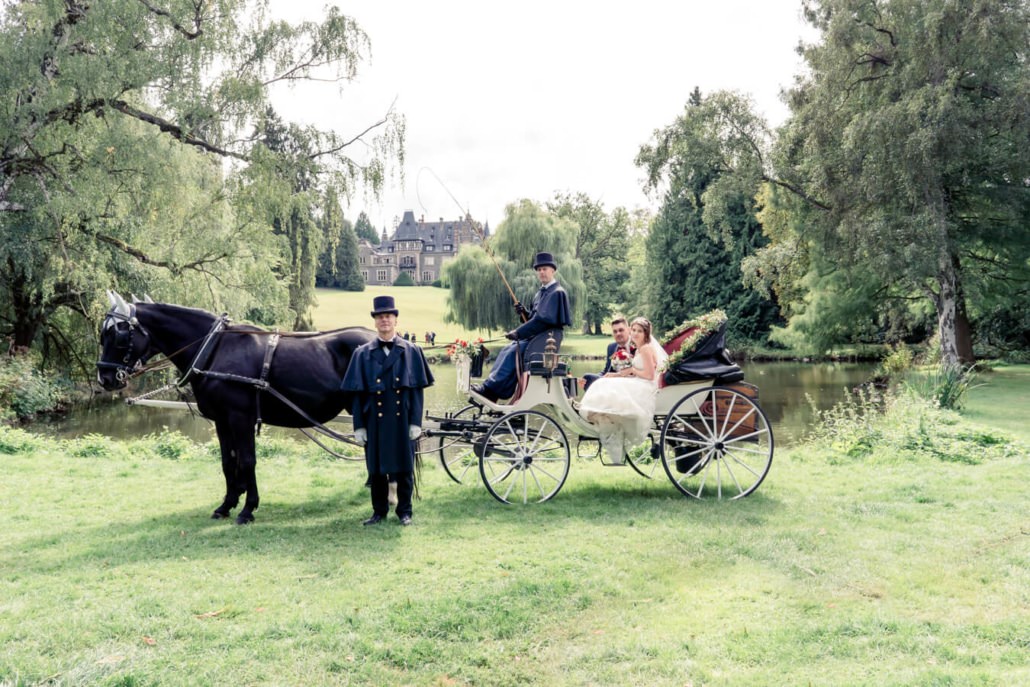 Brautpaar mit Hochzeitskutsche im Schlosspark