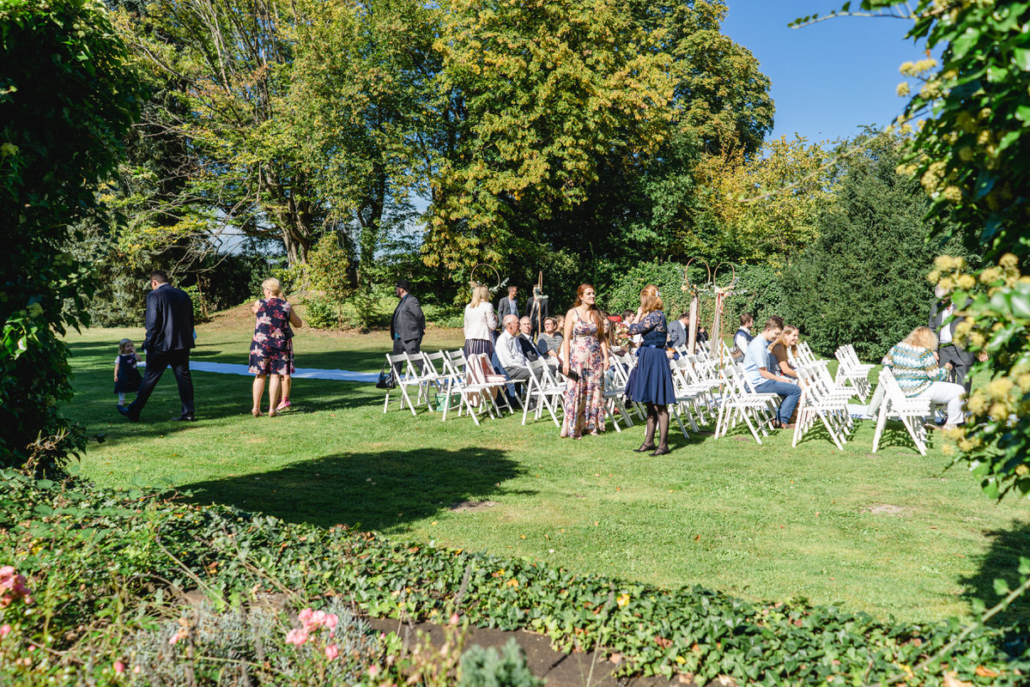 Hochzeitsgäste bei der Platzsuche im Garten für die freie Trauung