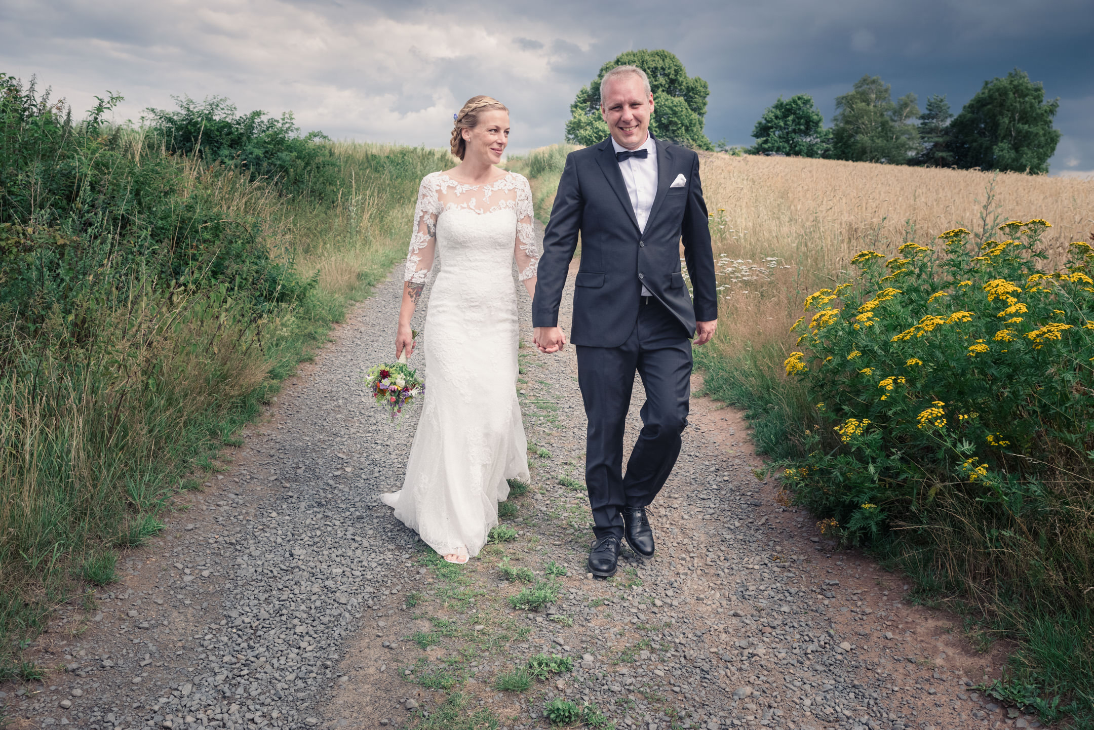 Brautpaar im Feld mit dramatischem Himmel