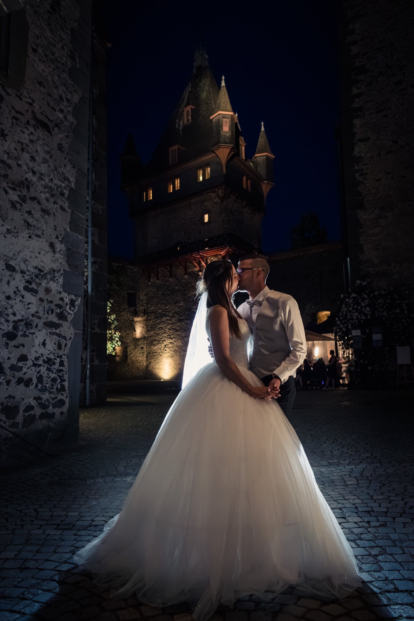 Hochzeitspaar küsst sich vor Schloss kulisse