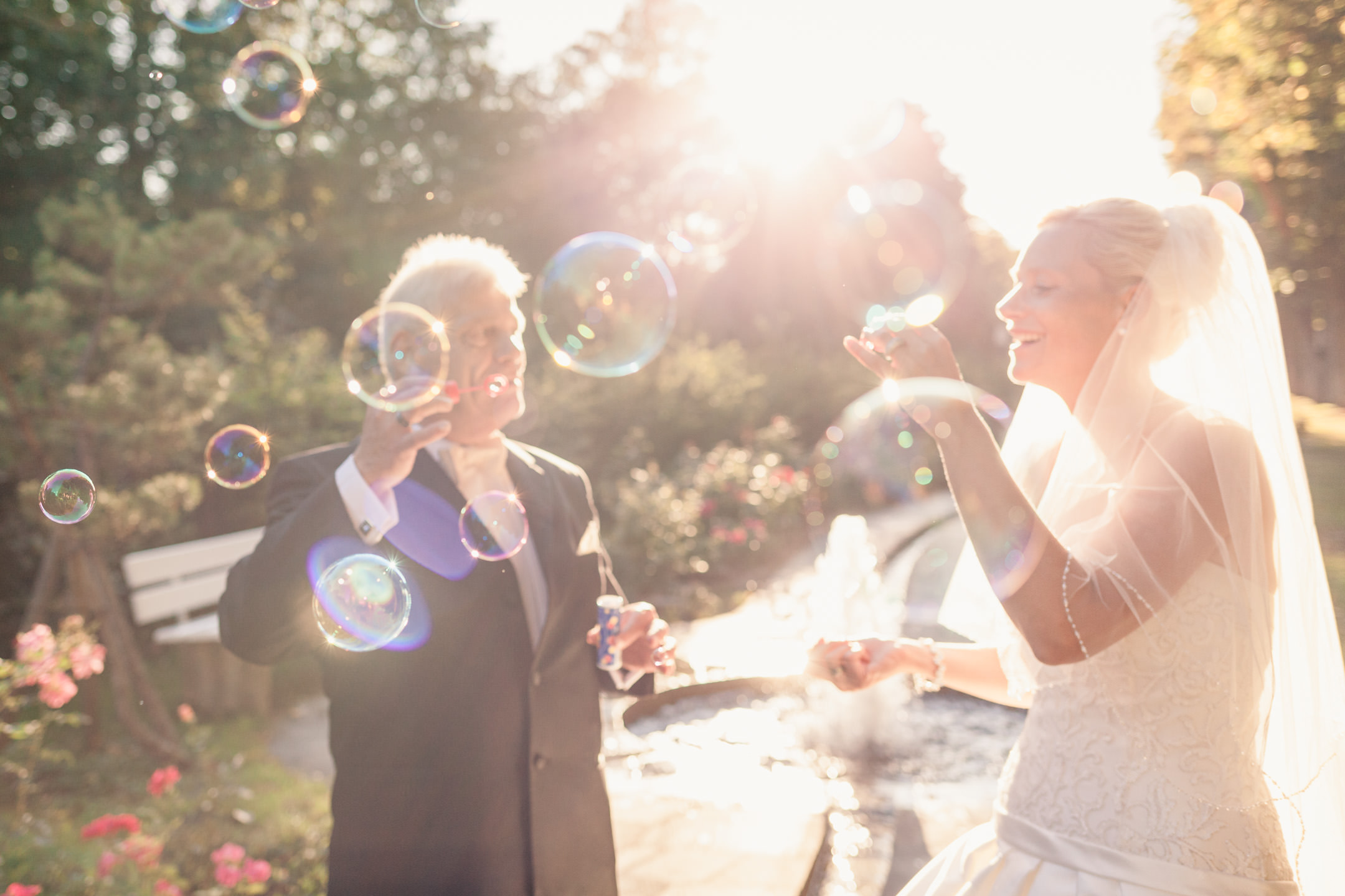 Hochzeitspaar beim Seifenblasen machen im Schlosspark.