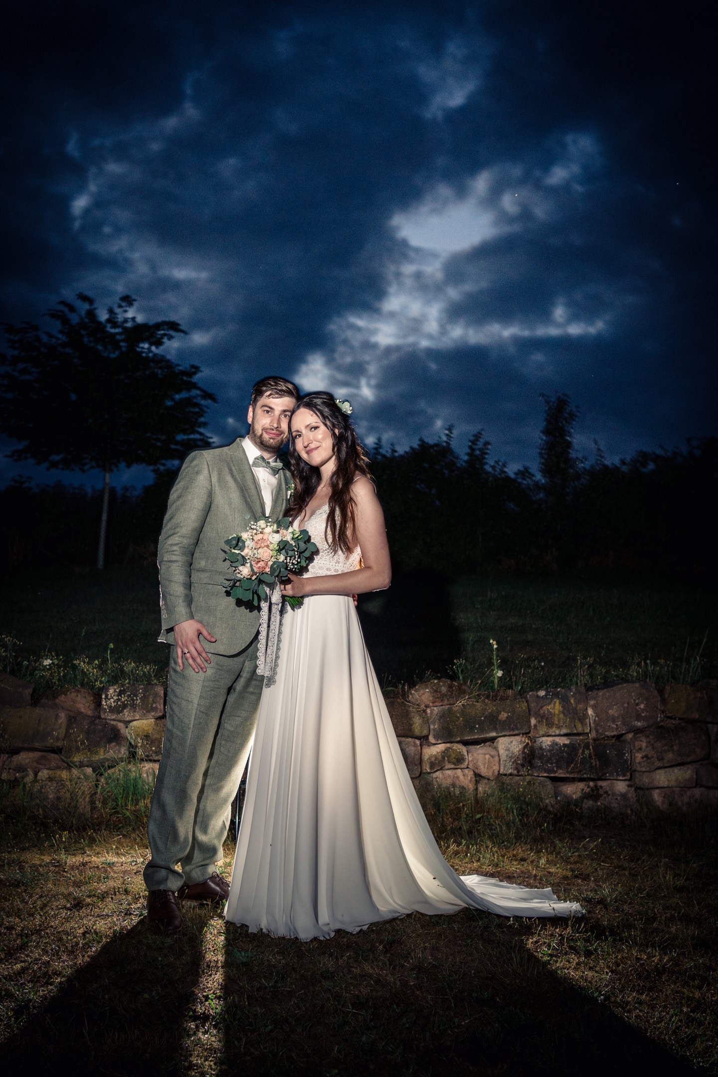 Hochzeitspaar in Blauestunde vor dramatischem Himmel.