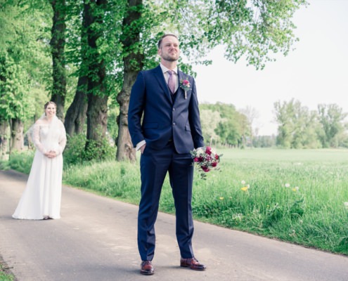 Bräutigam wartet mit Brautstrauß auf seine Braut beim Firstlook-Shooting