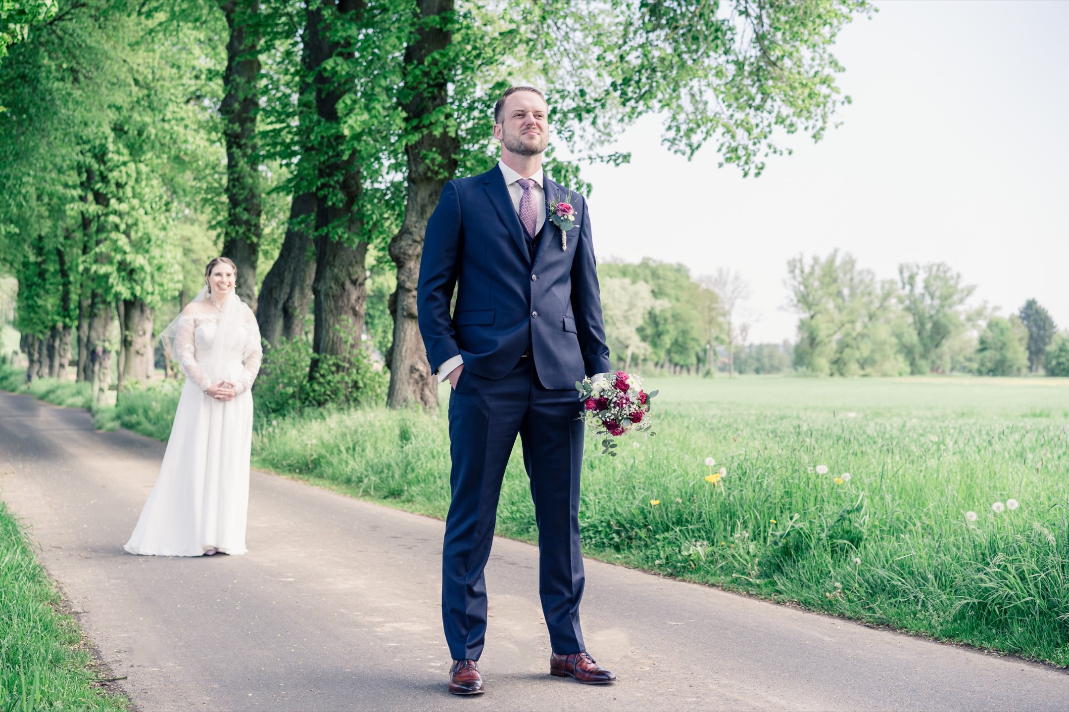 Bräutigam wartet mit Brautstrauß auf seine Braut beim Firstlook-Shooting