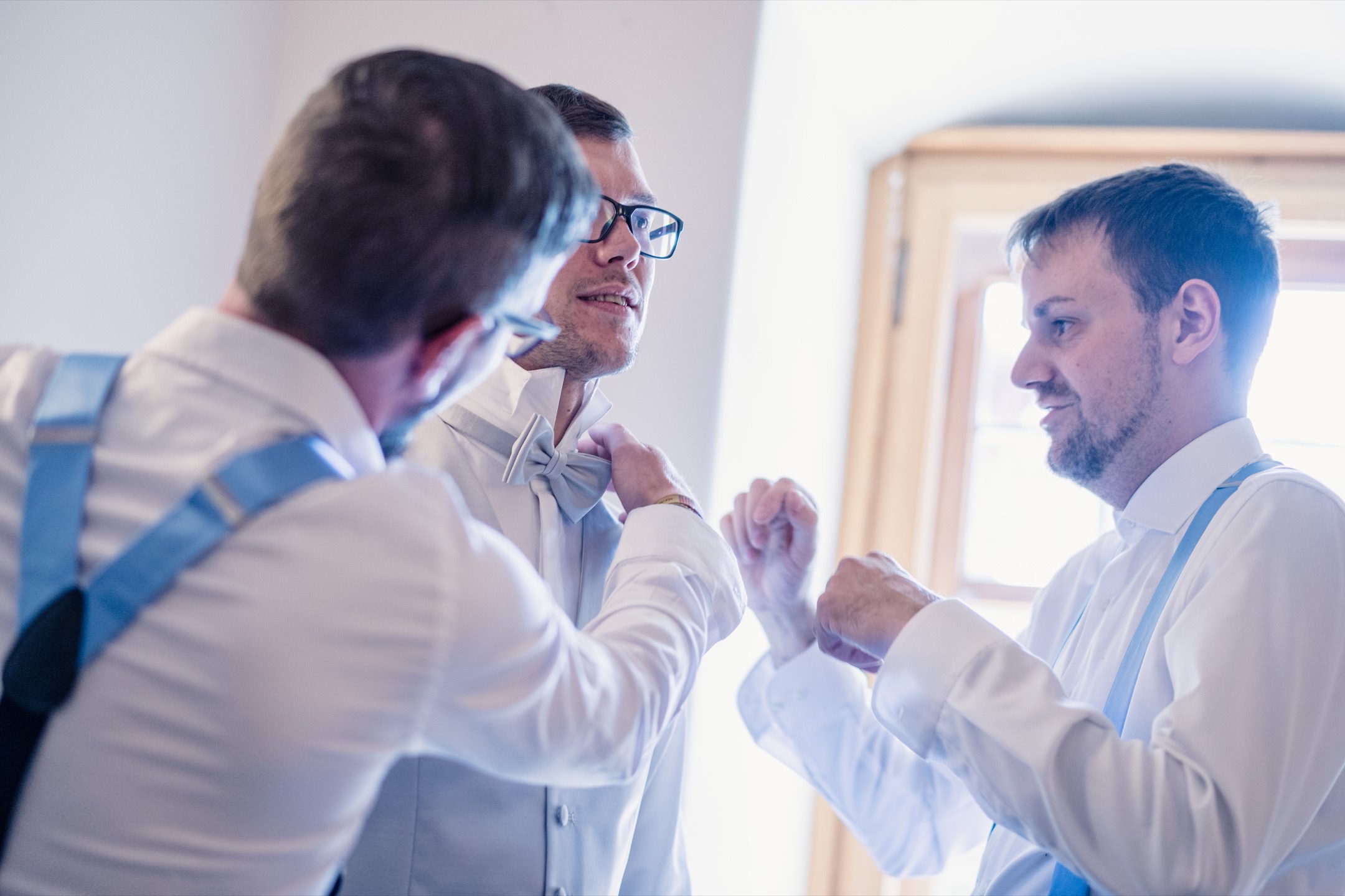 Unterstützung für den Bräutigam von seinen Groomsmen beim anlegen der Fliege